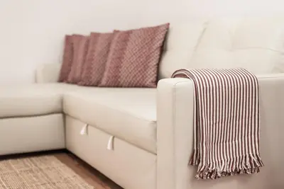 a white couch with a pillow and a blanket at GuestReady - Terracota Bureau in Porto