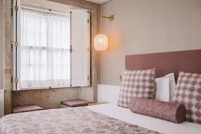 a bedroom with a bed with two pillows and a window at Gran Cruz House in Porto