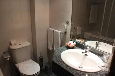 a bathroom with a sink and a toilet and a mirror at Seculo Hotel in Porto