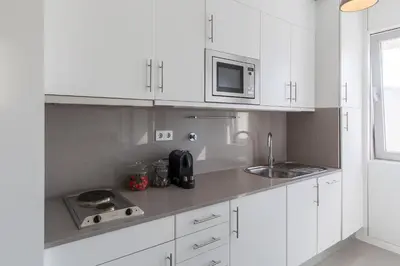 a white kitchen with a sink and a microwave at Aposentus - Arrábida Studio in Vila Nova de Gaia