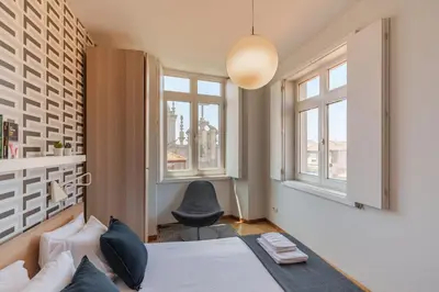 a bedroom with a bed and a chair and windows at Shining View Apartments in Porto