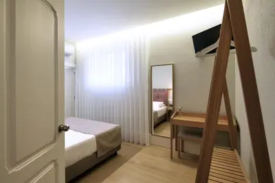 a small room with a bed and a mirror at The Rex Hotel Porto - Mansion House - Private Parking in Porto