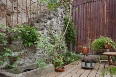 a garden with a wooden deck with plants and a fence at Cale Guest House in Porto