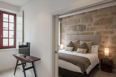 a bedroom with a bed with a stone wall at Porto Deluxe Suites in Porto