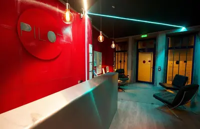 a room with a red wall with chairs and lights at PILOT Design Hostel & Bar in Porto