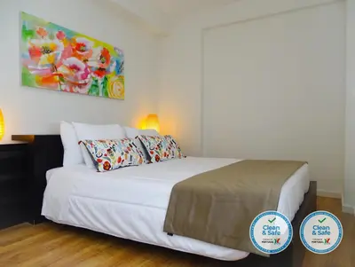 a bedroom with a white bed with a painting on the wall at RS Porto Vilar in Porto
