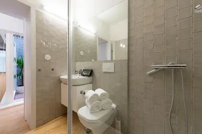 a bathroom with a toilet and a glass shower at BmyGuest - Villa Lóios Terrace Apartment in Porto