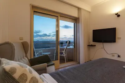a bedroom with a bed and a television and a balcony at Porto Gaia River View 8 by MP in Vila Nova de Gaia