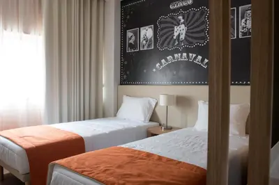 two beds in a hotel room with a poster on the wall at Porto Coliseum Hotel in Porto