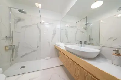 a white bathroom with a sink and a shower at Bom Jardim Apartments in Porto