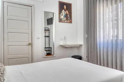a white bedroom with a bed and a window at Hotel Borsalino in Porto