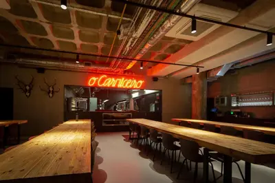 a restaurant with wooden tables and a neon sign at Zero Box Lodge Porto in Porto