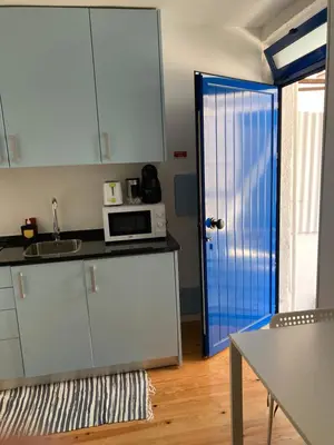 a kitchen with white cabinets and a blue door at J3M Houses in Porto