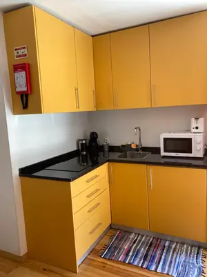 a kitchen with yellow cabinets and a microwave at J3M Houses in Porto