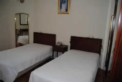 a bedroom with a bed with chairs and a table at Hotel Peninsular- Porto in Porto