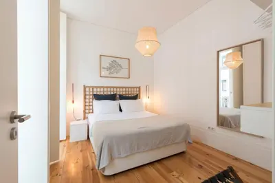 a white bedroom with a bed and a large mirror at Light Blue Apartment in Porto