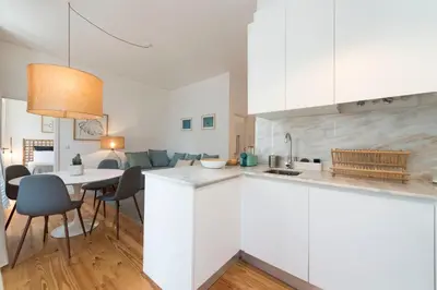 a kitchen and living room with white cabinets and a table at Light Blue Apartment in Porto