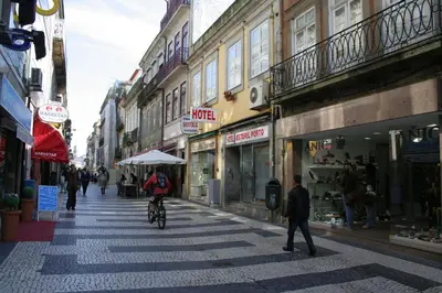 a person riding a bike down a street in a city at Hotel Estoril Porto in Porto