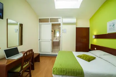 a bedroom with a bed and a desk with a laptop at Hotel Estoril Porto in Porto