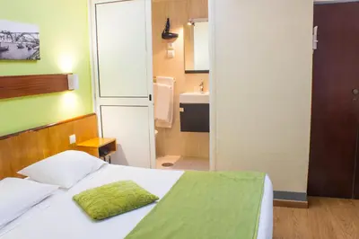 a small bedroom with a bed and a bathroom at Hotel Estoril Porto in Porto