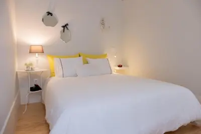 a white bedroom with a large white bed with yellow pillows at Alda's Vintage Apartments with Free Parking in Porto