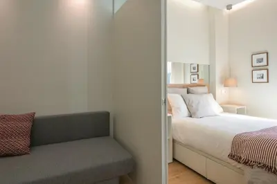 a white bedroom with a bed and a chair at Inn Oporto Downtown New Apartments in Porto