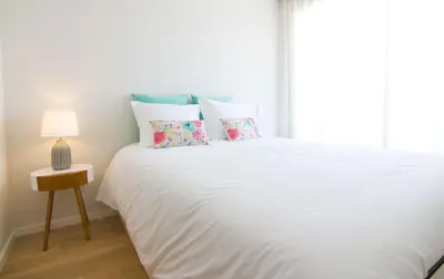a white bed with pillows and a lamp on a table at MH Duo in Porto