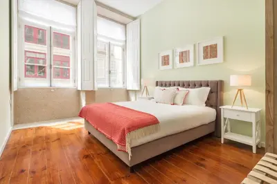 a bedroom with a bed with a red blanket and two windows at FAISAMA • Porto Apartments in Porto