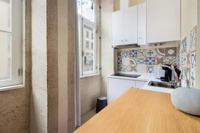 a kitchen with white cabinets and a wooden table at FAISAMA • Porto Apartments in Porto