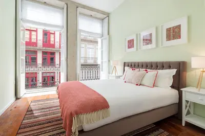 a bedroom with a large bed and two windows at FAISAMA • Porto Apartments in Porto