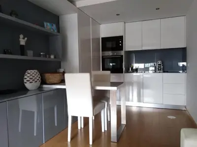 a kitchen with white cabinets and a table and chairs at Maestro Appartment in Porto