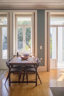 a dining room with a wooden table and two windows at Central location with garden & equipped kitchen in Porto