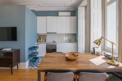 a dining room with a wooden table and blue walls at Central location with garden & equipped kitchen in Porto
