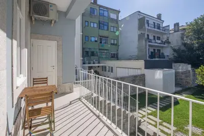 a balcony with a wooden bench and some buildings at Central location with garden & equipped kitchen in Porto