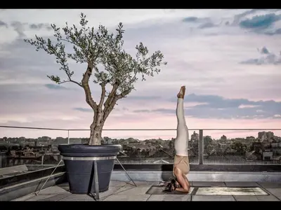 a woman doing a handstand on a ledge with a tree at Hotel Moon & Sun Porto in Porto