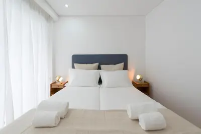 a white bedroom with a large bed with white pillows at Bruno's Downtown Apartment in Porto