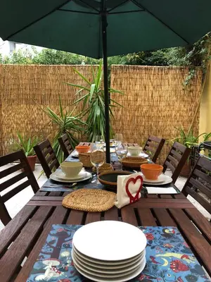 a wooden table with plates and an umbrella at BS VILLAS RC PORTO in Porto