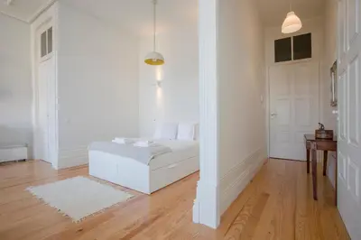a white bedroom with a bed and a door at Downtown Spacious Studio in Porto