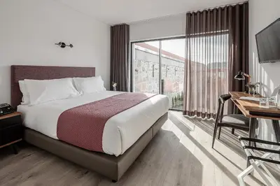 a bedroom with a bed and a desk and a window at Caléway Hotel in Vila Nova de Gaia