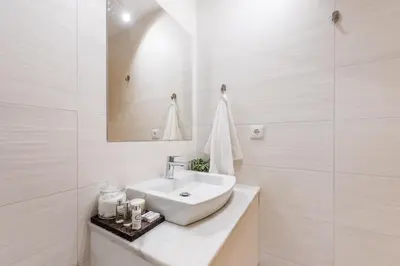 a white bathroom with a sink and a mirror at SOBRI Cork House - Sustainable Loft in Porto