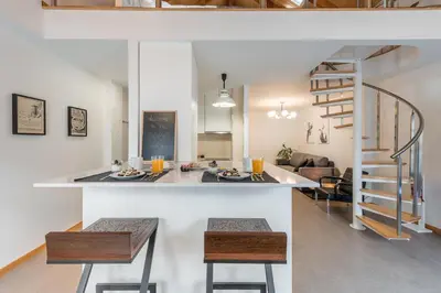 a kitchen and living room with a counter and a staircase at SOBRI Cork House - Sustainable Loft in Porto