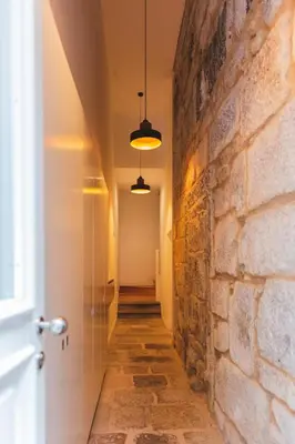 a hallway with a stone wall and two lights at Aposentus - Your fabulous home next to Ribeira in Porto