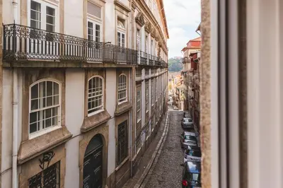 an alley between two buildings with cars parked at Aposentus - Your fabulous home next to Ribeira in Porto