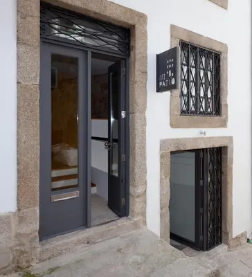 a black door on a white building with a sign at InPatio Guest House in Porto
