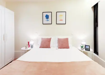 a white bedroom with a large white bed with two tables at HM - Ribeira São João 1B in Porto
