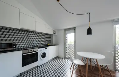 a kitchen with white cabinets and a table and chairs at PortoSoul Trindade in Porto