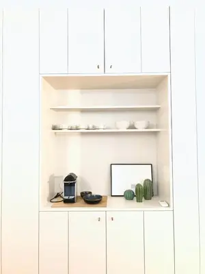 a white kitchen with white cabinets and a shelf at Lóios Flat in Porto