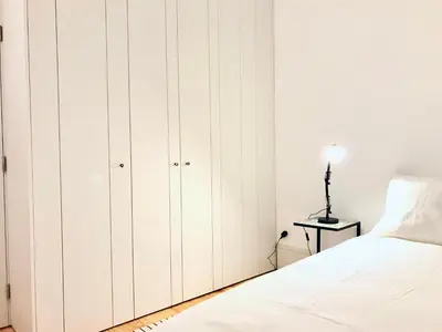 a bedroom with white cabinets and a white bed at Lóios Flat in Porto