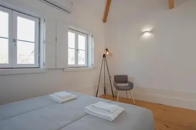 a white bedroom with a bed and a chair at Liiiving in Porto | Historic & Sunny Terrace in Porto
