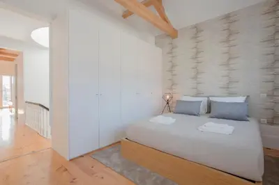 a white bedroom with a large bed with blue pillows at Liiiving in Porto | Historic & Sunny Terrace in Porto